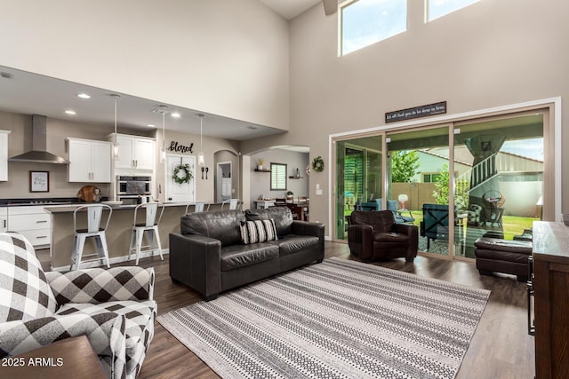 living room featuring a high ceiling, dark hardwood / wood-style flooring, and a wealth of natural light