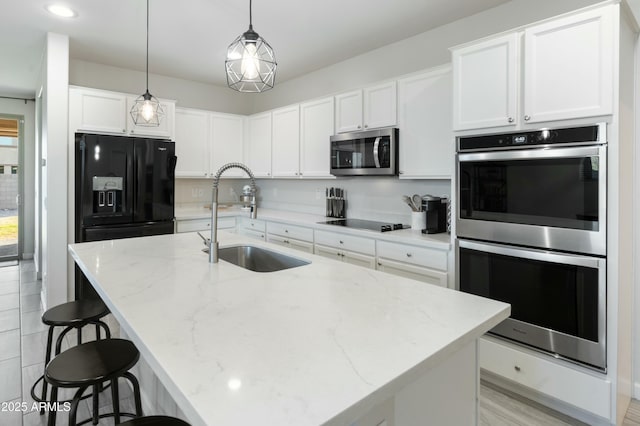 kitchen featuring a breakfast bar, black appliances, white cabinets, and a sink