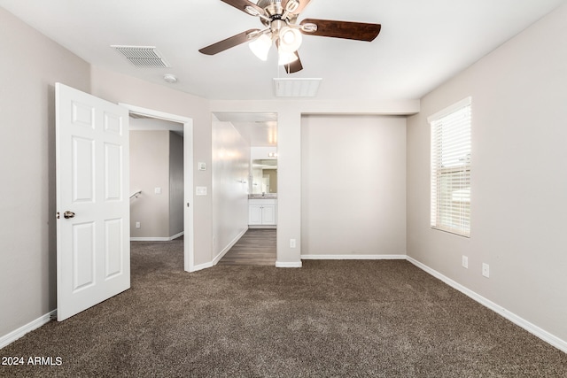 unfurnished bedroom with dark carpet and ceiling fan