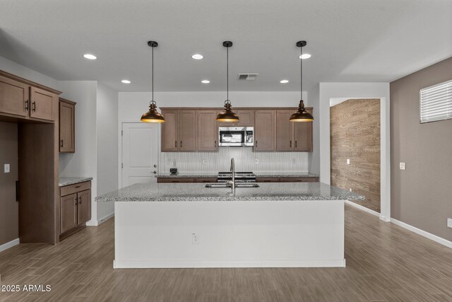 4539 Charro Ct, Wickenburg, AZ 85390 - kitchen with appliances with stainless steel finishes, tasteful backsplash, wood finished floors, a kitchen island with sink, and recessed lighting