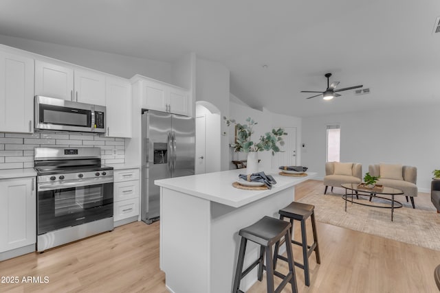 kitchen with visible vents, white cabinetry, appliances with stainless steel finishes, tasteful backsplash, and a kitchen bar