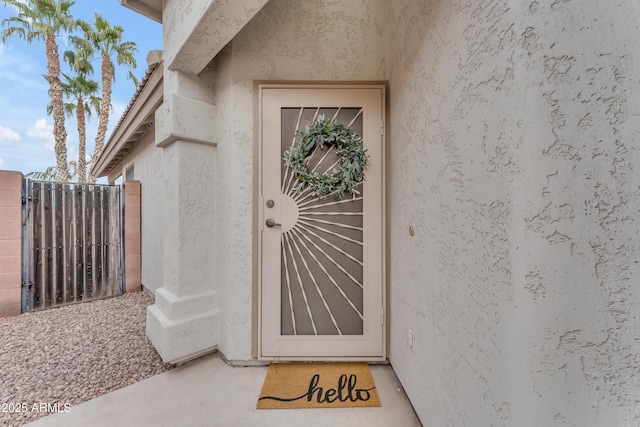 entrance to property with fence and stucco siding