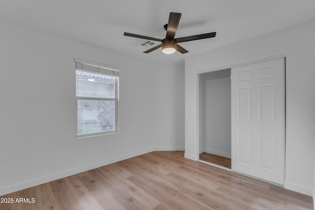 unfurnished bedroom with light wood finished floors, a closet, baseboards, and a ceiling fan