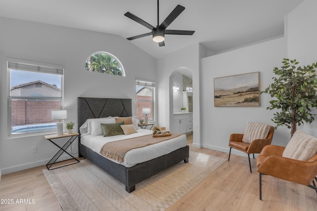 bedroom with arched walkways, a ceiling fan, vaulted ceiling, wood finished floors, and baseboards