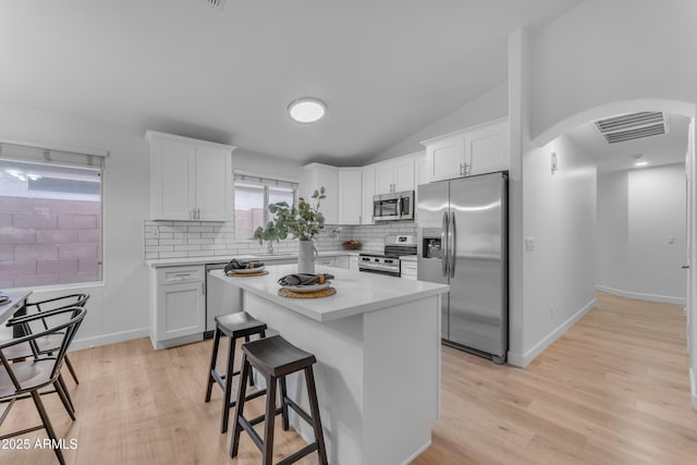 kitchen with arched walkways, stainless steel appliances, visible vents, and white cabinetry