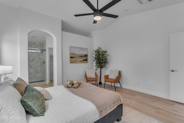 bedroom featuring baseboards, arched walkways, ceiling fan, a spacious closet, and light wood-type flooring