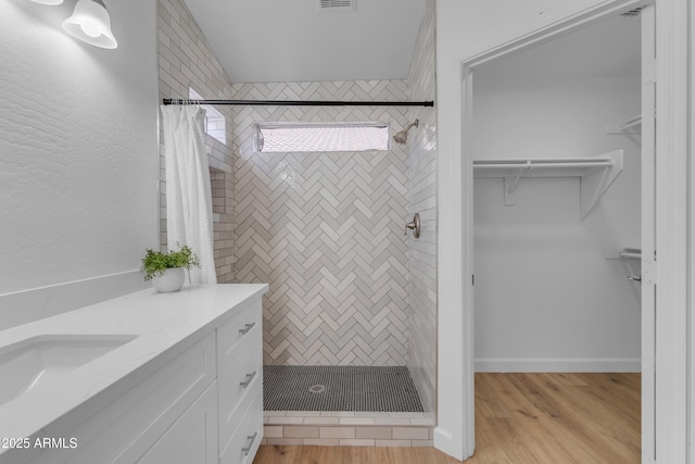 bathroom featuring a shower stall, visible vents, a walk in closet, and wood finished floors