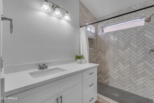 full bathroom featuring a textured wall, a shower stall, and vanity