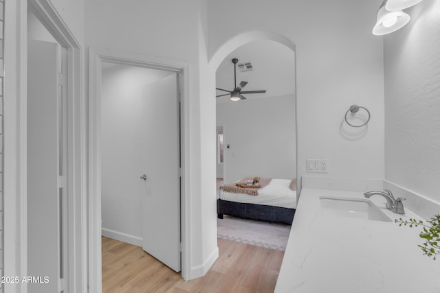 bathroom featuring ceiling fan, ensuite bathroom, wood finished floors, a sink, and visible vents