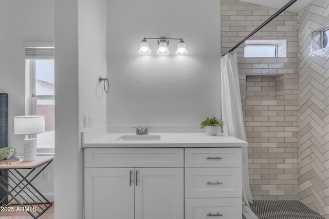 bathroom with tiled shower and vanity