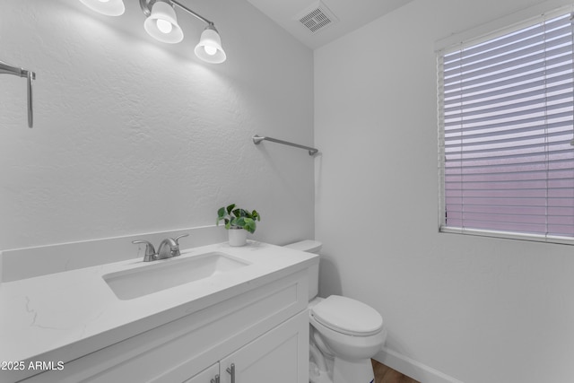 bathroom with visible vents, vanity, toilet, and baseboards