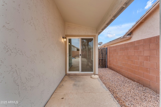 doorway to property with stucco siding, fence, and a patio