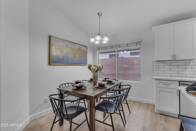 dining space with lofted ceiling, light wood-type flooring, a chandelier, and baseboards