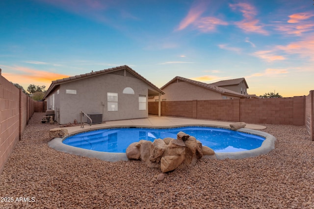 pool at dusk featuring a fenced backyard, cooling unit, a fenced in pool, and a patio