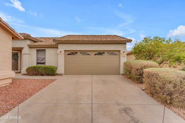 view of front of home with a garage, concrete driveway, a tiled roof, and stucco siding