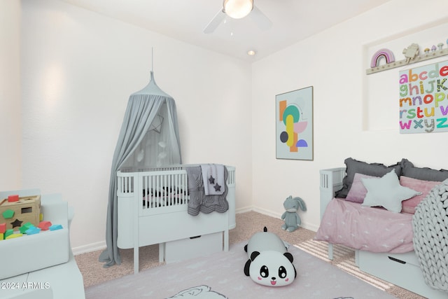 bedroom with ceiling fan, carpet, and a crib