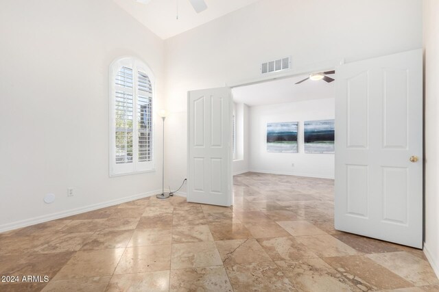 empty room featuring high vaulted ceiling and ceiling fan