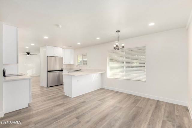 kitchen featuring white cabinets, ceiling fan with notable chandelier, hanging light fixtures, stainless steel fridge, and kitchen peninsula