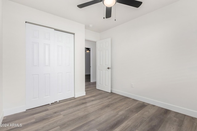 unfurnished bedroom featuring ceiling fan, a closet, and wood-type flooring