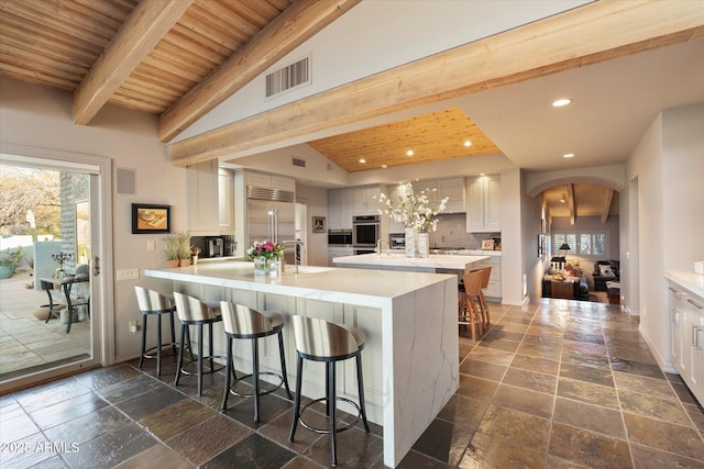 kitchen with white cabinetry, wood ceiling, a breakfast bar area, and appliances with stainless steel finishes