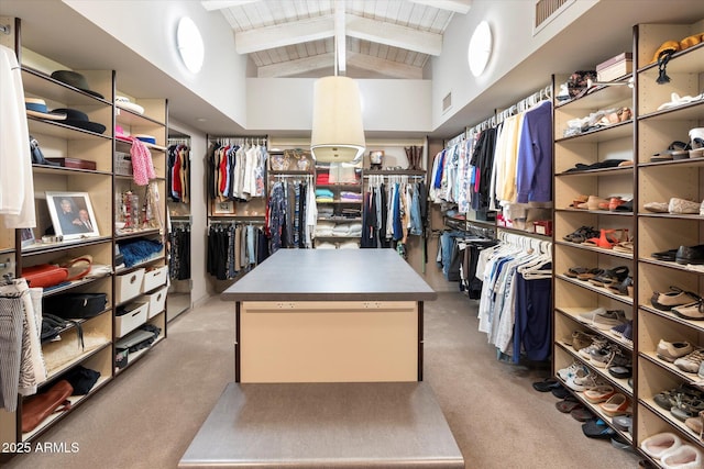 walk in closet featuring light colored carpet and lofted ceiling with beams