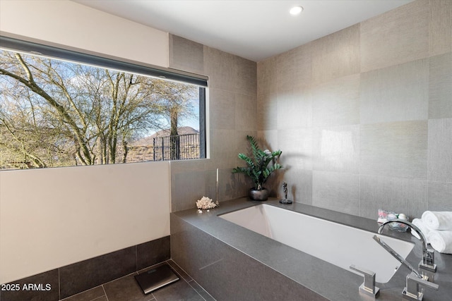 bathroom with tile patterned floors, tile walls, and tiled tub