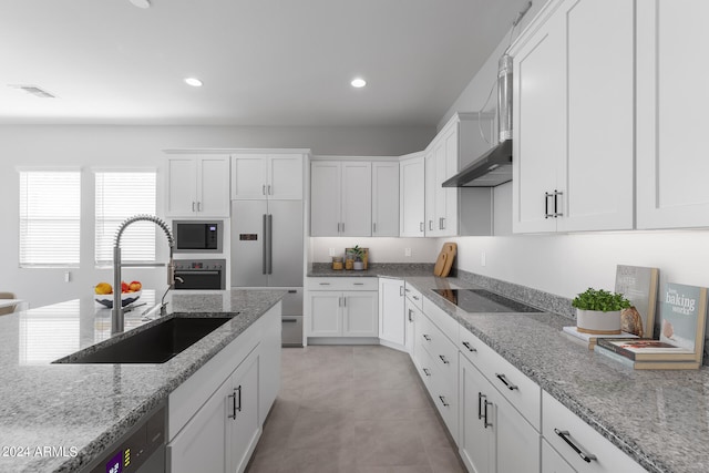 kitchen featuring built in appliances, light tile floors, white cabinetry, sink, and light stone counters