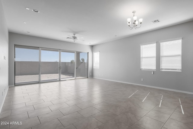 unfurnished room featuring plenty of natural light, ceiling fan with notable chandelier, and light tile flooring