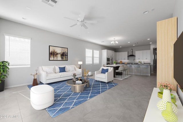 tiled living room with sink and ceiling fan with notable chandelier