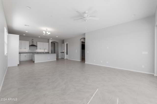 unfurnished living room with ceiling fan with notable chandelier, sink, and light tile floors