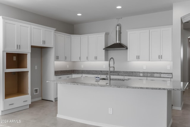 kitchen with a center island with sink, white cabinetry, and wall chimney exhaust hood