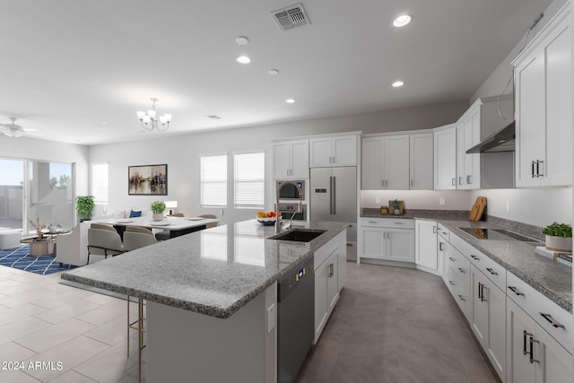 kitchen featuring white cabinets, built in appliances, a center island with sink, and ceiling fan with notable chandelier