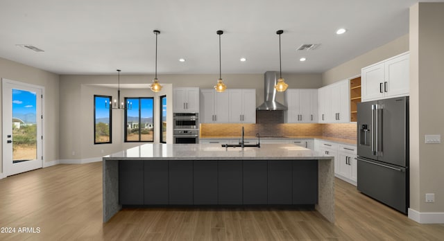 kitchen featuring wall chimney exhaust hood, appliances with stainless steel finishes, sink, and white cabinetry