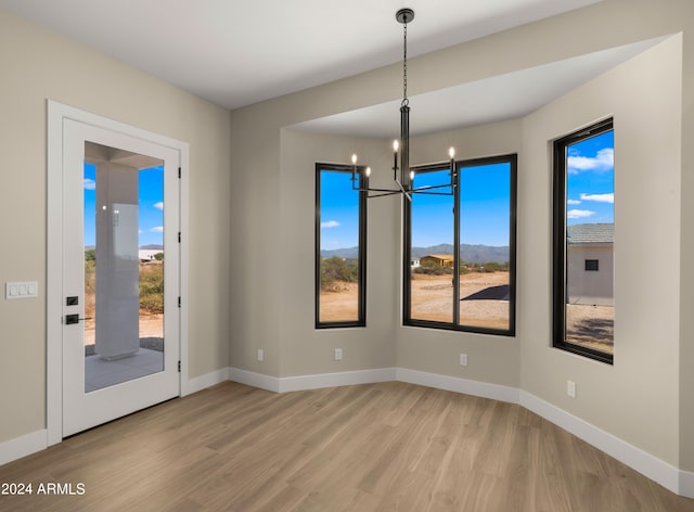 unfurnished dining area featuring an inviting chandelier and light hardwood / wood-style flooring