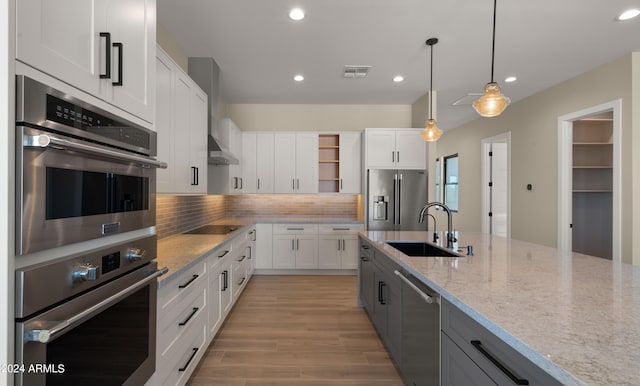 kitchen with white cabinetry, sink, stainless steel appliances, and decorative light fixtures