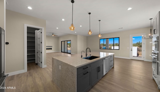 kitchen with gray cabinets, light hardwood / wood-style flooring, sink, light stone counters, and stainless steel appliances