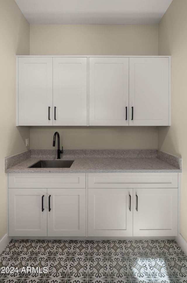 bar with white cabinets, sink, and light tile patterned floors