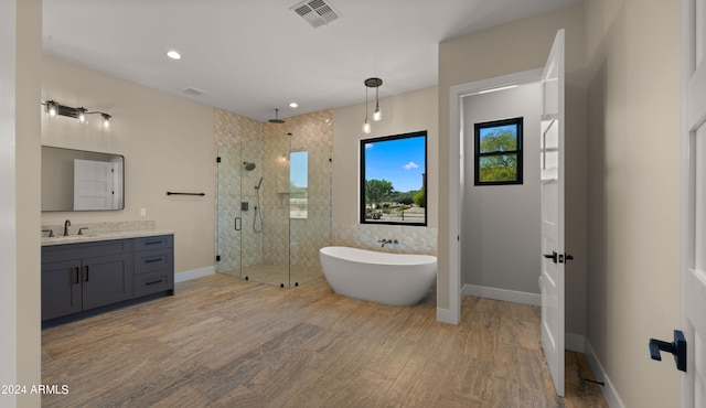 bathroom with hardwood / wood-style floors, shower with separate bathtub, and vanity