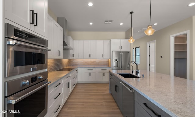 kitchen featuring appliances with stainless steel finishes, hanging light fixtures, white cabinetry, and sink