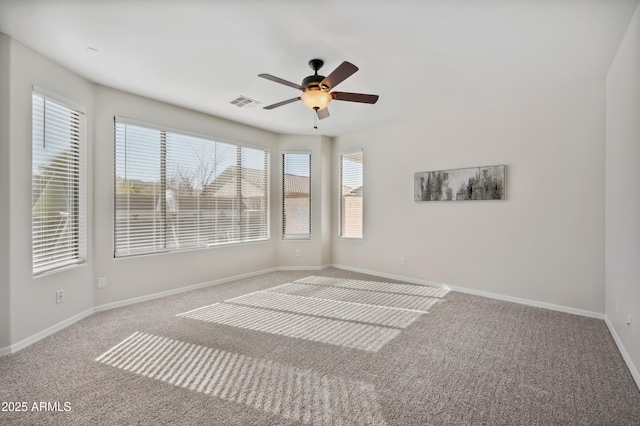 carpeted spare room with plenty of natural light, visible vents, ceiling fan, and baseboards