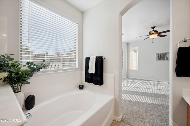 bathroom featuring a ceiling fan, a garden tub, and baseboards