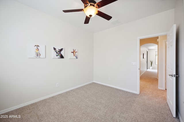 unfurnished bedroom featuring baseboards, arched walkways, ceiling fan, and carpet flooring