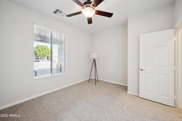 spare room with baseboards, visible vents, ceiling fan, and light colored carpet