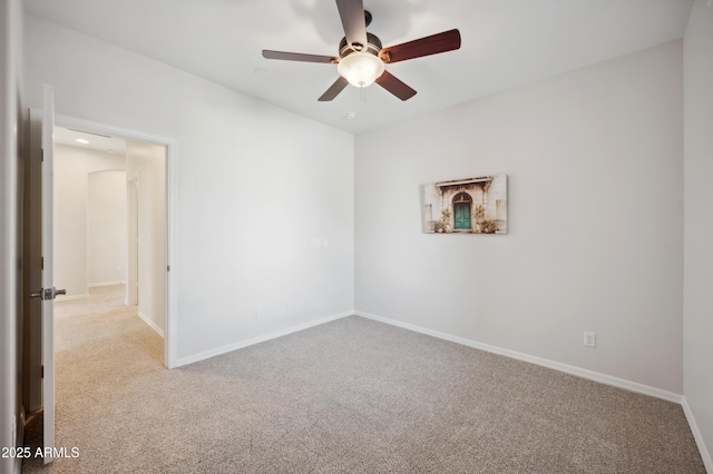 spare room with carpet, baseboards, and a ceiling fan