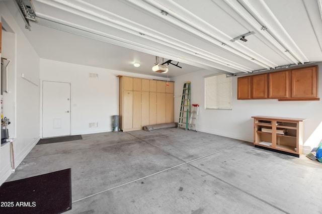 garage featuring a garage door opener, visible vents, and baseboards