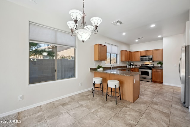 kitchen featuring a peninsula, a sink, visible vents, baseboards, and appliances with stainless steel finishes