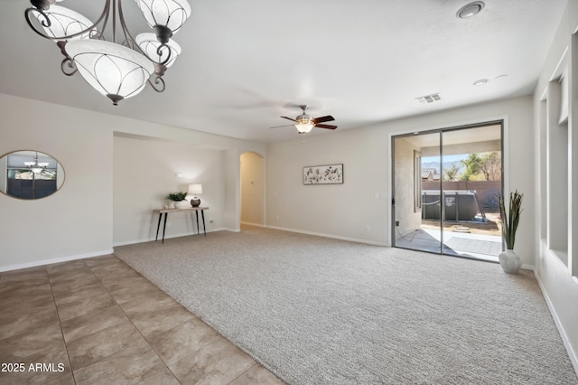 tiled spare room featuring carpet, arched walkways, visible vents, baseboards, and ceiling fan with notable chandelier