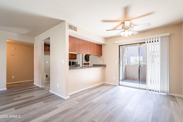 kitchen with light wood-style floors, visible vents, stainless steel microwave, and brown cabinetry