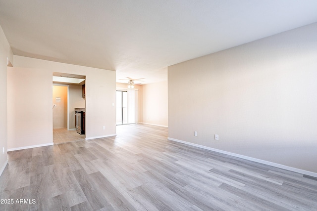 empty room featuring light wood finished floors, ceiling fan, and baseboards