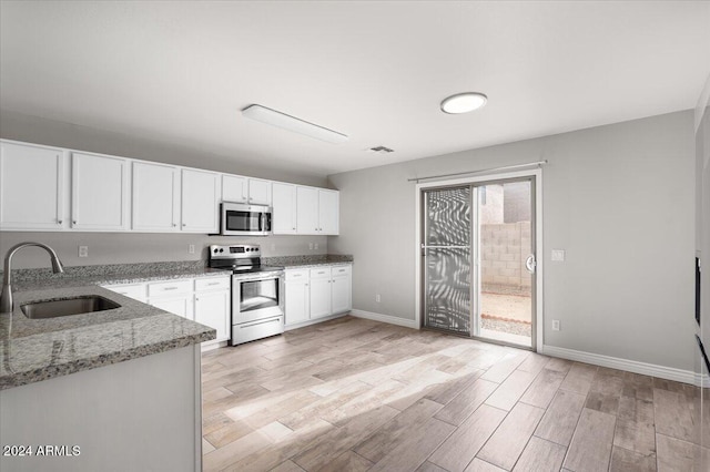 kitchen with sink, light stone counters, plenty of natural light, white cabinets, and appliances with stainless steel finishes